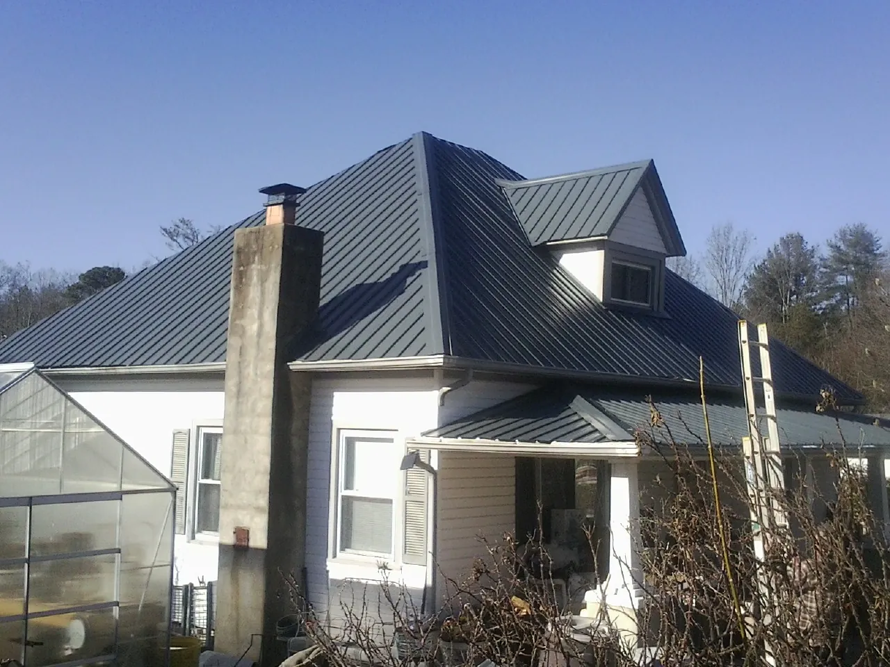 Dark blue standing seam metal roof on a white farmhouse with dormer — Slate & Tile Roof Repair by Roofing Brothers in Suquamish