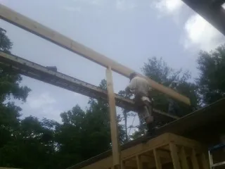 Carpenter setting a ridge beam over a new addition frame — Ice Dam Removal by Roofing Brothers in Suquamish