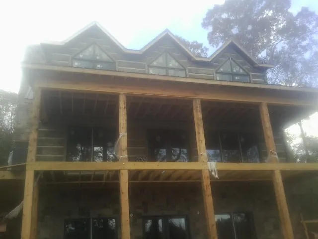 Dormers and porch framing on a large log home under construction — Roof Coating work by our crew in Suquamish