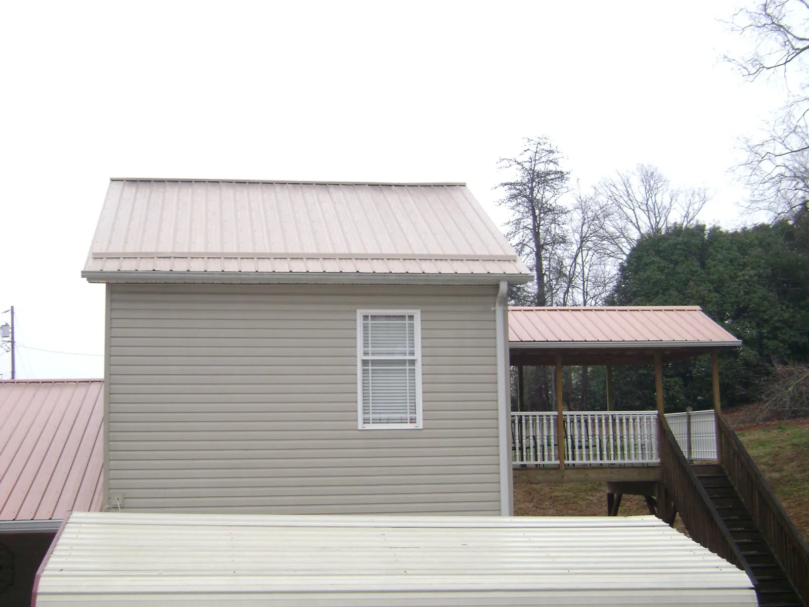 Tan metal roofs on a two story addition and attached porch, from a Roof Replacement job in Suquamish