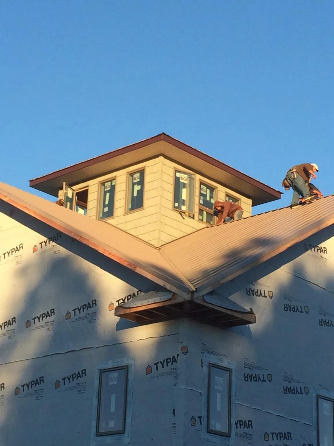 Roofers working around a rooftop cupola on a new metal roof at sunset — Roof Waterproofing in Suquamish by Roofing Brothers